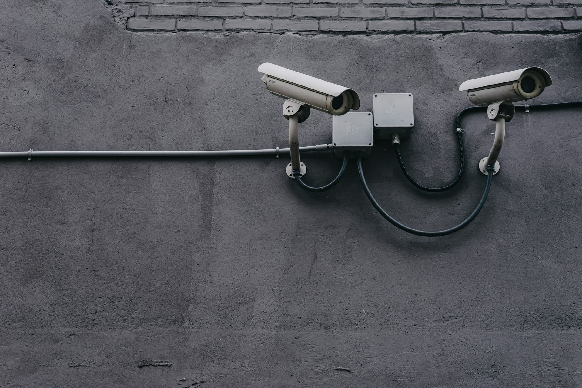 Dos cámaras de videovigilancia instaladas en el exterior de un edificio, con conduit y cableado protegido